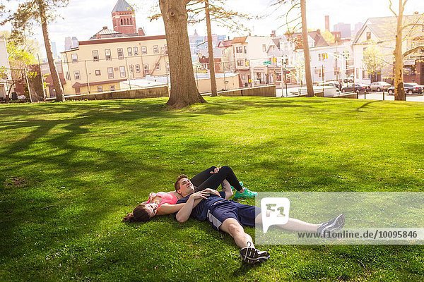 Romantic young sporty couple lying on grass in park