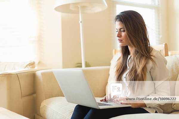 Young woman sitting on sofa  using laptop