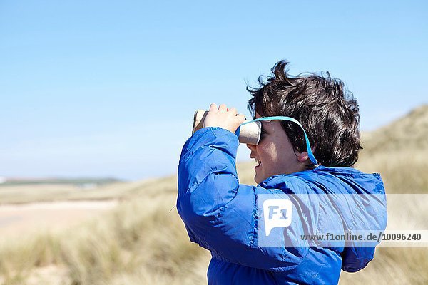 Young boy on beach  looking through pretend binoculars