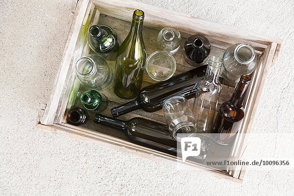 Holzkiste mit verschiedenen leeren Flaschen für das Recycling