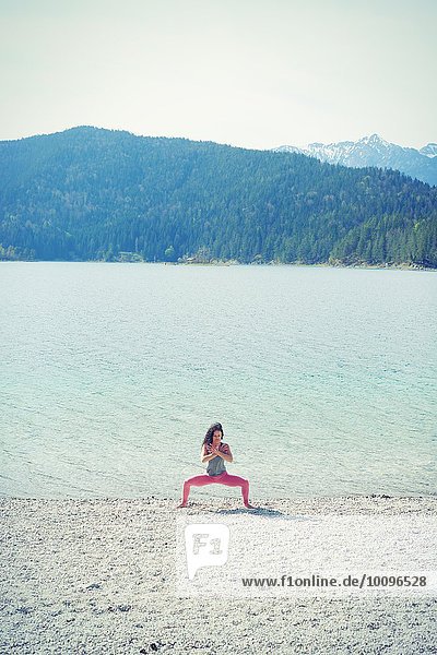 Mittlere erwachsene Frau  am See  in Yogastellung