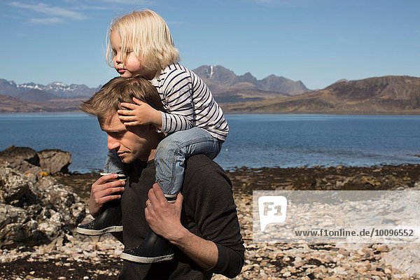 Father carrying son on shoulders  Loch Eishort  Isle of Skye  Hebrides  Scotland