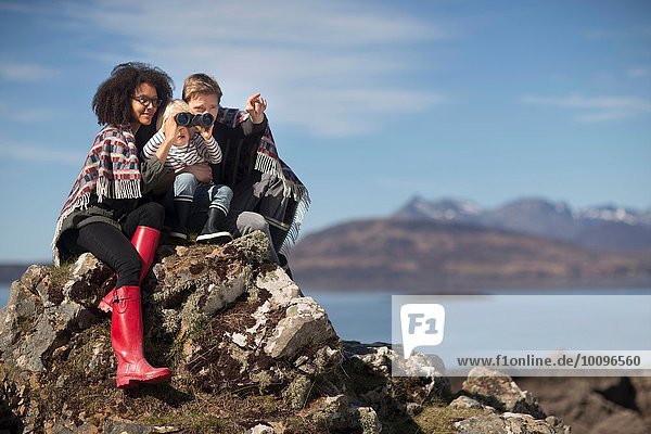 Familie auf Felsen sitzend  Junge mit Binokularen