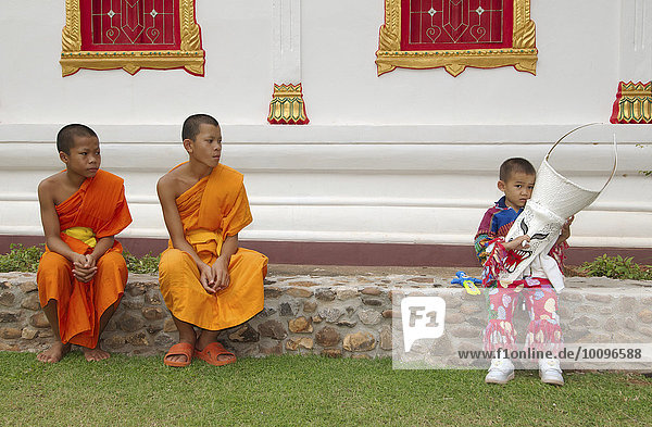 Zwei Novizen und ein Junge,  der eine Maske hält,  Phi Ta Khon Masken-Festival,  beim Wat Phon Chai,  Amphoe Dan Sai,  Provinz Loei,  Thailand,  Asien