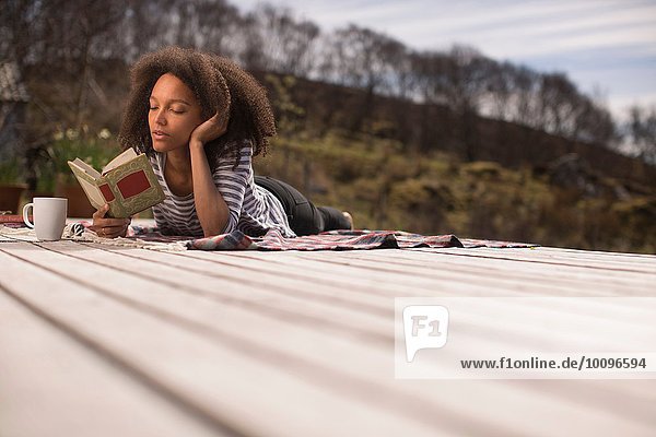 Mid adult woman lying down  reading book