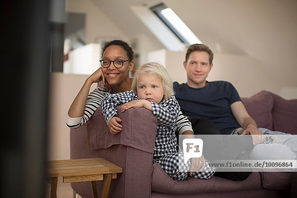 Family sitting on sofa watching television