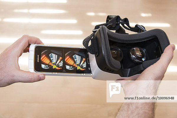 Mann hält ZEISS VR ONE Virtual Reality Kunststoff-VR-Brille mit Halterung für Samsung Galaxy S5 Android Smartphone  Caaaaardboard! App für Android auf dem Display