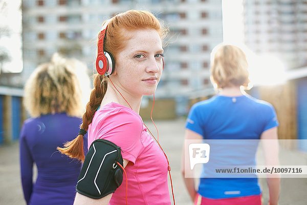 Porträt einer Frau mit Armband und Kopfhörer vor dem Training mit Blick über die Schulter auf die Kamera