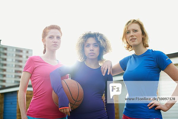 Porträt von drei Frauen  die gemeinsam einen Basketball halten.
