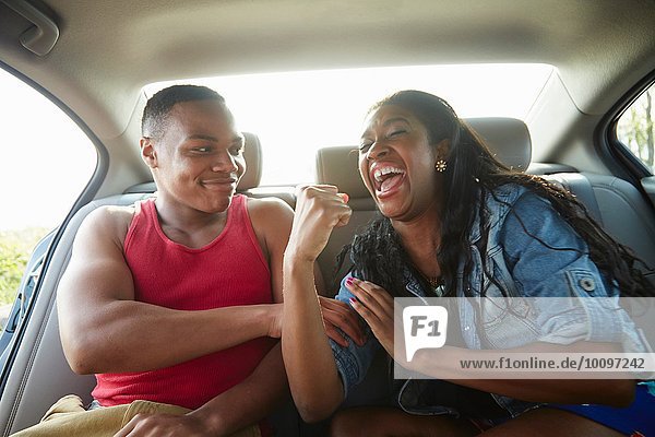 Young couple in car laughing  woman flexing muscles
