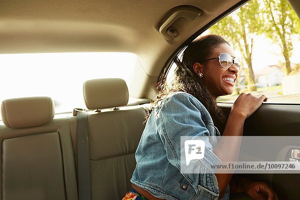Junge Frau mit Sonnenbrille und Blick aus dem Autofenster