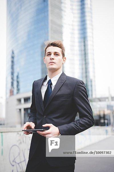 Portrait of young businessman commuter using digital tablet.
