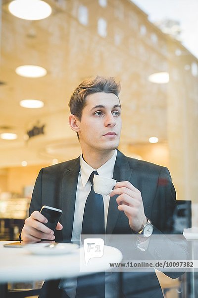 Porträt eines jungen Geschäftsmannes  der im Cafe sitzt  mit digitalem Tablett und Handy.