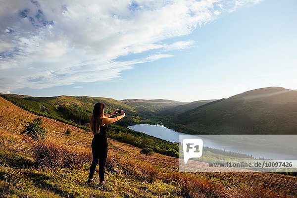 Junge Frau fotografiert das Talybont Reservoir in Glyn Collwn Valley  Brecon Beacons  Powys  Wales.