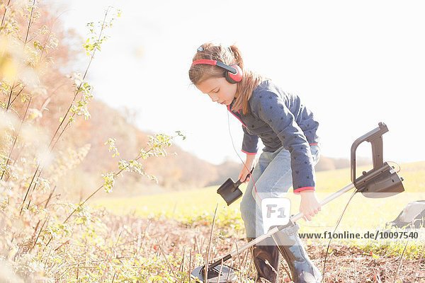 Girl crouching with spade and metal detector in field