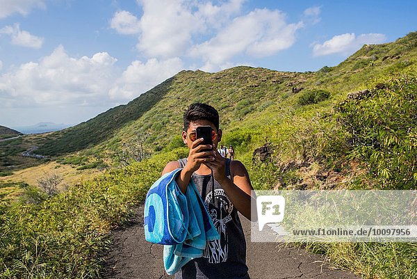 Portrait of young man taking smartphone selfie on Makapuu coast path  Oahu  Hawaii  USA