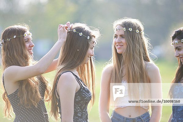 Teenagermädchen beim Anziehen und Tragen von Daisy Chain Headdresses im Park