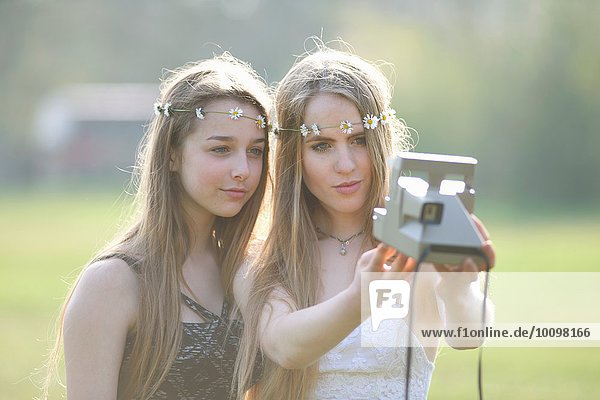 Zwei Teenager-Mädchen im Park mit Sofortbildkamera Selfie