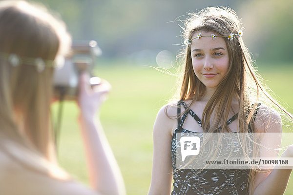 Teenagermädchen fotografiert beste Freundin mit Sofortbildkamera im Park