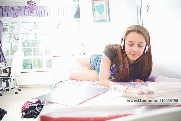 Teenagermädchen beim Betrachten des Schallplattencovers und beim Hören von Kopfhörern im Schlafzimmer