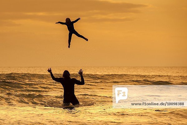 Vater wirft Sohn in die Luft  im Meer bei Sonnenuntergang  Lahinch  Clare  Irland