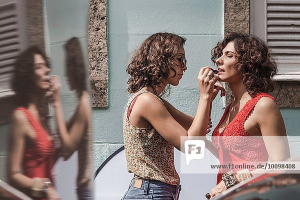 Behind the scenes of an urban fashion shoot with make up artist applying lipstick to model