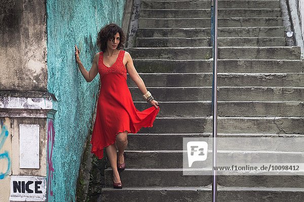 Fashion model wearing red dress walking down steps