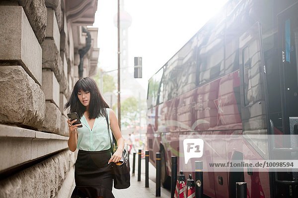 Junge Geschäftsfrau  mit Smartphone  im Freien  Shanghai  China