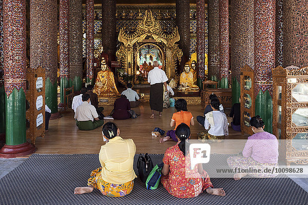 Menschen meditieren vor Buddha-Statuen  Shwedagon-Pagode  Yangon  Myanmar  Asien
