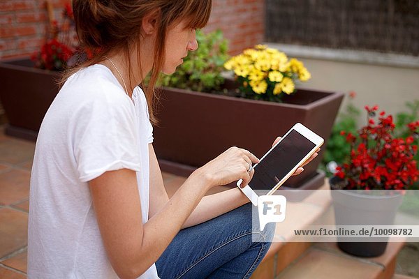 Seitenansicht der mittleren erwachsenen Frau im Freien mit Hilfe eines digitalen Tabletts