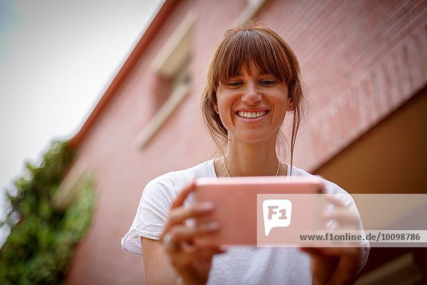 Low und Ansicht der mittleren erwachsenen Frau mit Smartphone  lächelnd