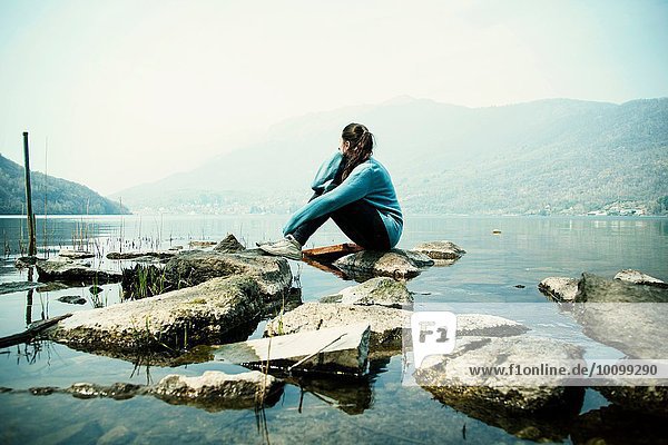 Junge Frau auf Felsen sitzend mit Blick auf den Mergozzo-See  Verbania  Piemonte  Italien