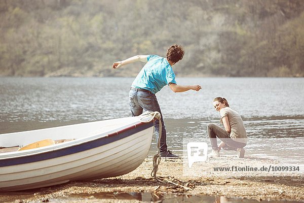 Young man and girlfriend skimming stones in Lake Mergozzo  Verbania  Piemonte  Italy