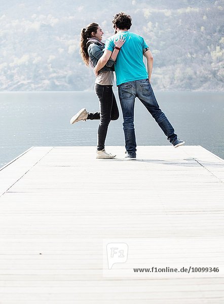 Young couple standing on one leg on pier at Lake Mergozzo  Verbania  Piemonte  Italy