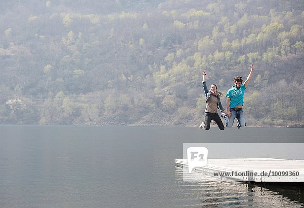 Junges Paar springt auf dem Pier am Mergozzo-See  Verbania  Piemonte  Italien