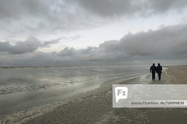 Spaziergänger bei schlechtem Wetter am Strand der Nordseeinsel,  Langeoog,  Ostfriesland,  Niedersachsen,  Deutschland,  Europa