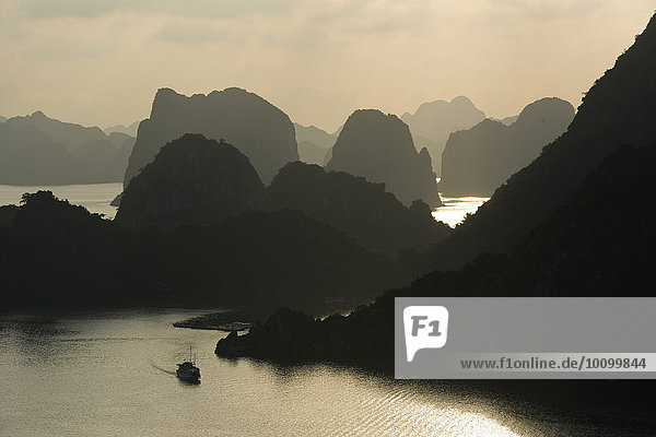 Boat on the water at sunset in the Ha Long Bay or Vinh Ha Long  limestone cliffs  UNESCO World Heritage Site  Gulf of Tonkin  North Vietnam  Vietnam  Asia