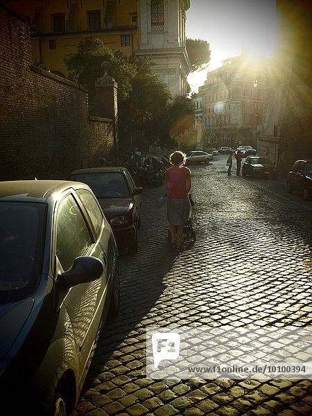 Frau im Gegenlicht am Abend auf einer alten Kopfsteinpflasterstraße  Rom  Italien  Europa