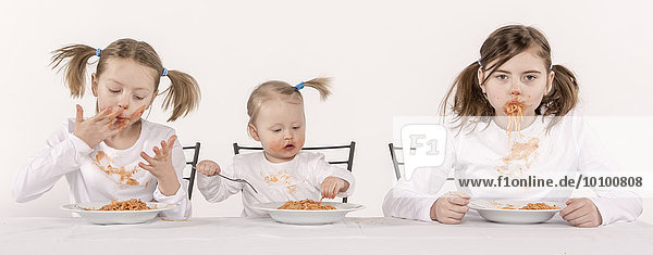 Three girls eating spaghetti at table