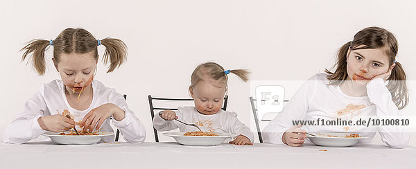 Three girls eating spaghetti at table