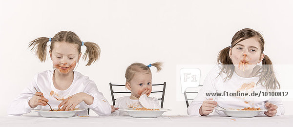 Drei Mädchen essen Spaghetti am Tisch