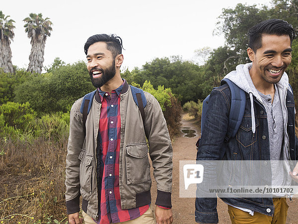 Two smiling young men walking in a park.