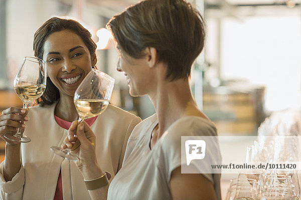 Lächelnde Frauen Weinverkostung Weißwein im Weinkeller