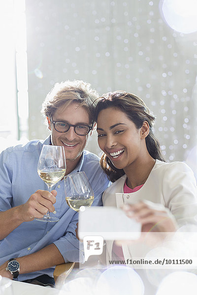 Couple with white wine taking selfie with camera phone