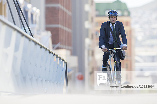 Businessman in suit and helmet riding bicycle in city