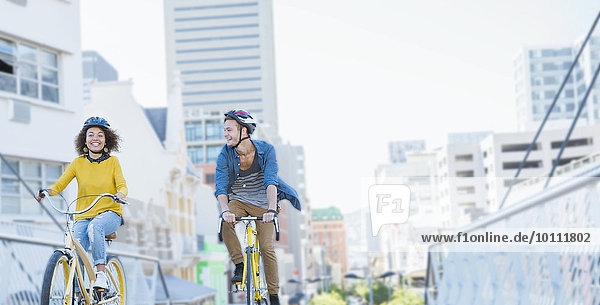 Freunde mit Helmen auf Fahrrädern über die städtische Fußgängerbrücke