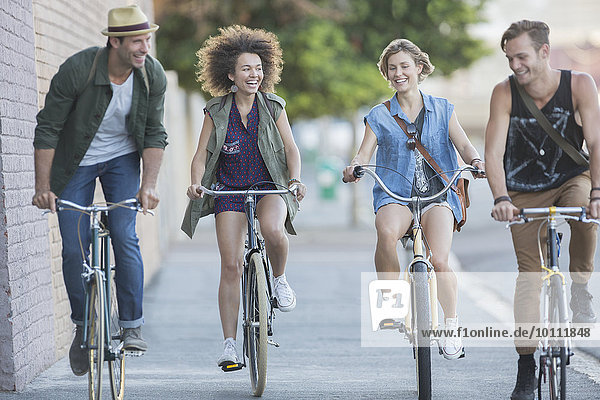 Friends riding bicycles on urban sidewalk