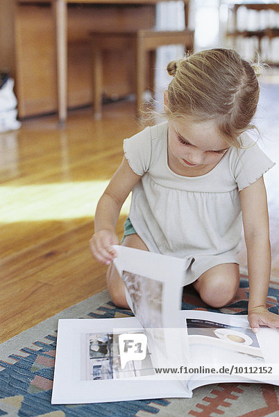 Young girl sitting on the floor  reading a lifestyle magazine.