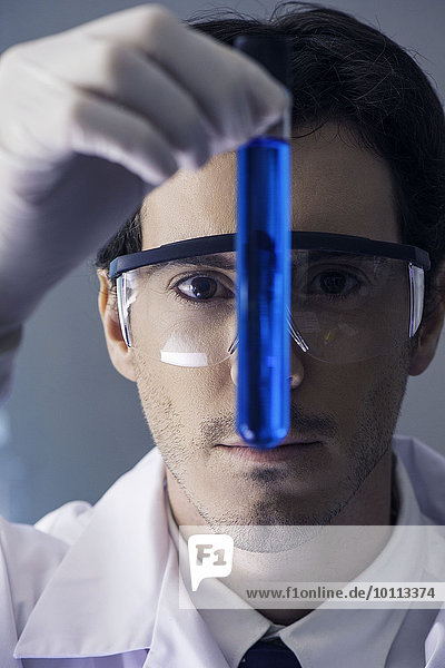 Chemiker untersuchen Reagenzglas mit blauer Flüssigkeit