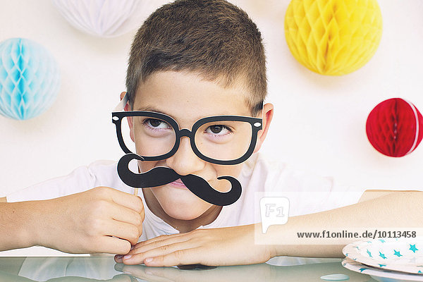 Junge mit gefälschter Brille und Schnurrbart bei einer Geburtstagsfeier  Portrait